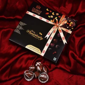 Black Happy Anniversary gift box by Dessert Spring Chocolate, elegantly placed on a luxurious red shining cloth background, perfect for celebrations in Bangalore.