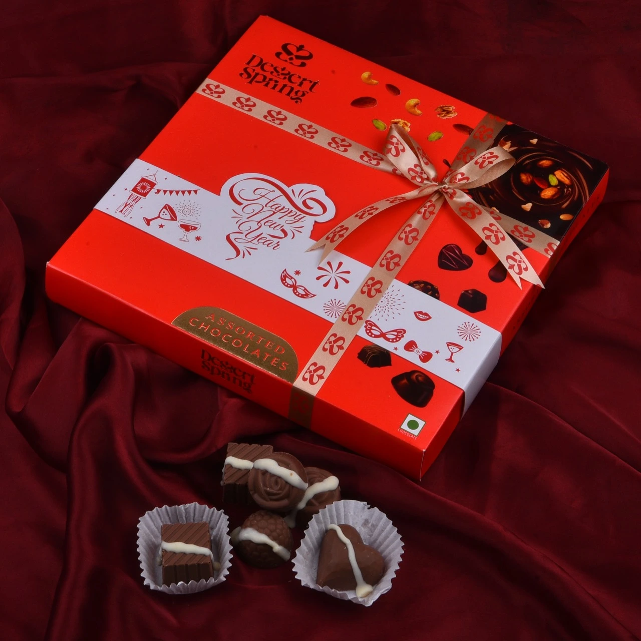 Happy New Year chocolate gift box by Dessert Spring Chocolate, displayed on a radiant red shining cloth background, perfect for festive gifting in Bangalore.